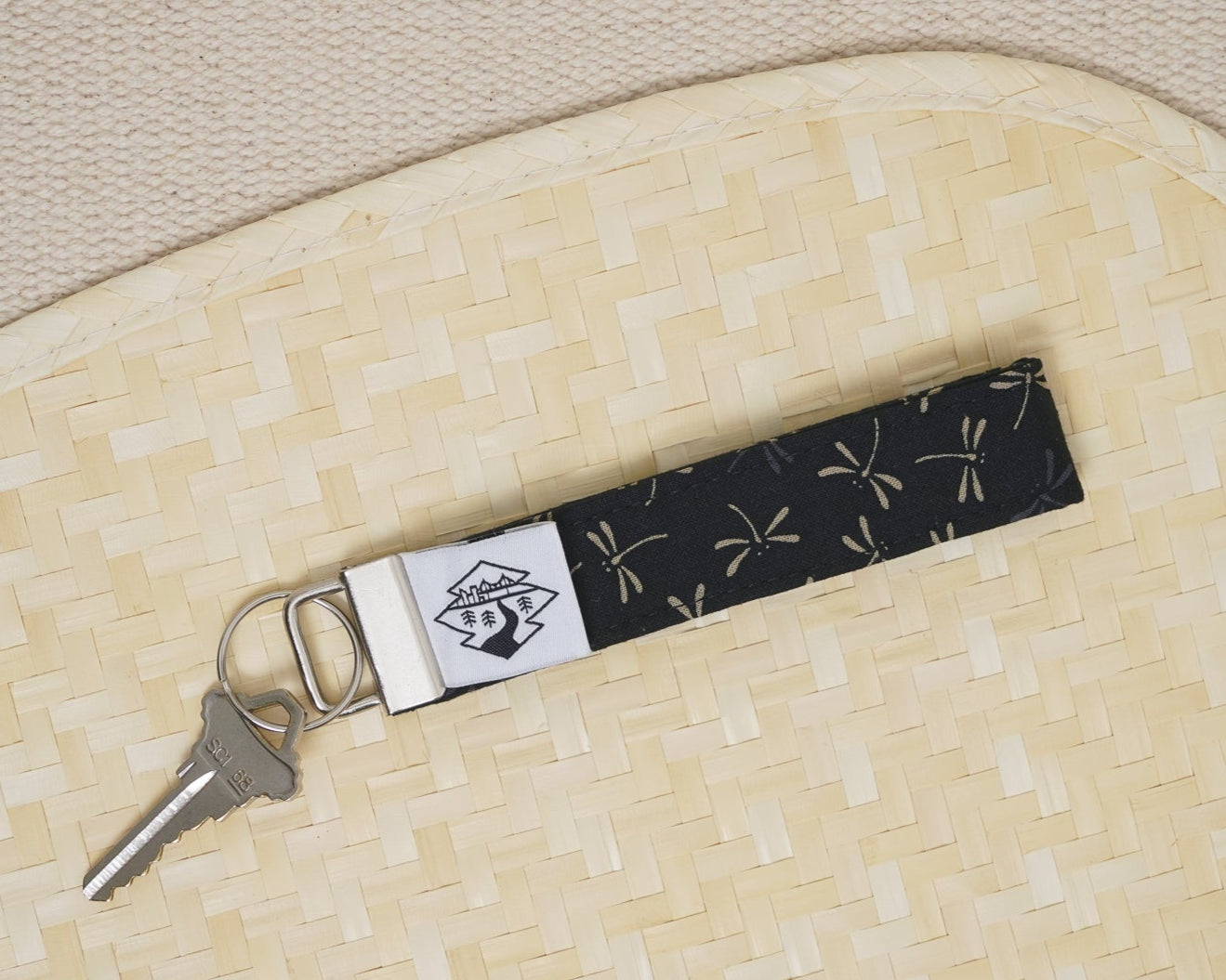 Keychain with a black and white pattern on a beige woven surface