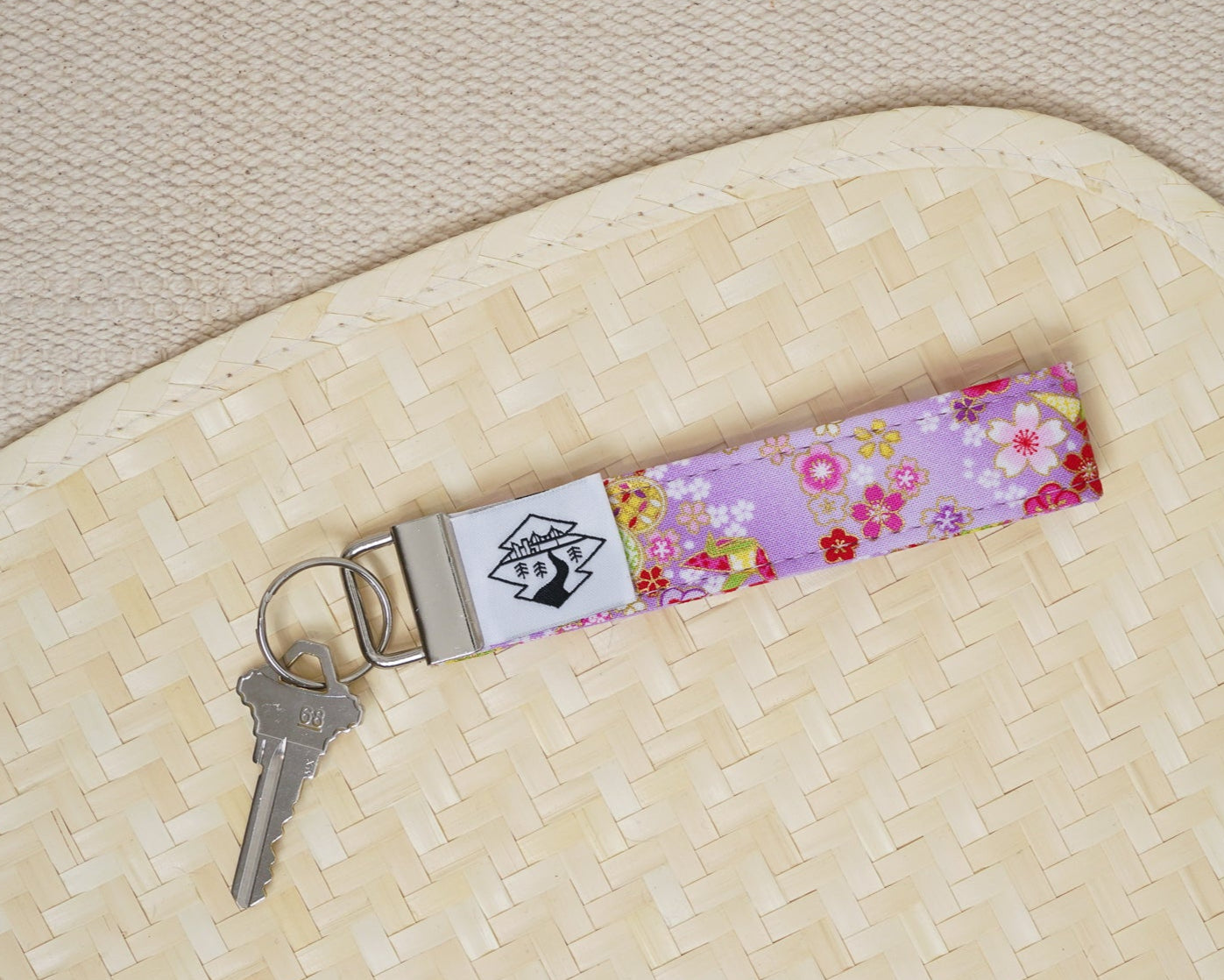 Floral keychain with a key on a textured beige surface
