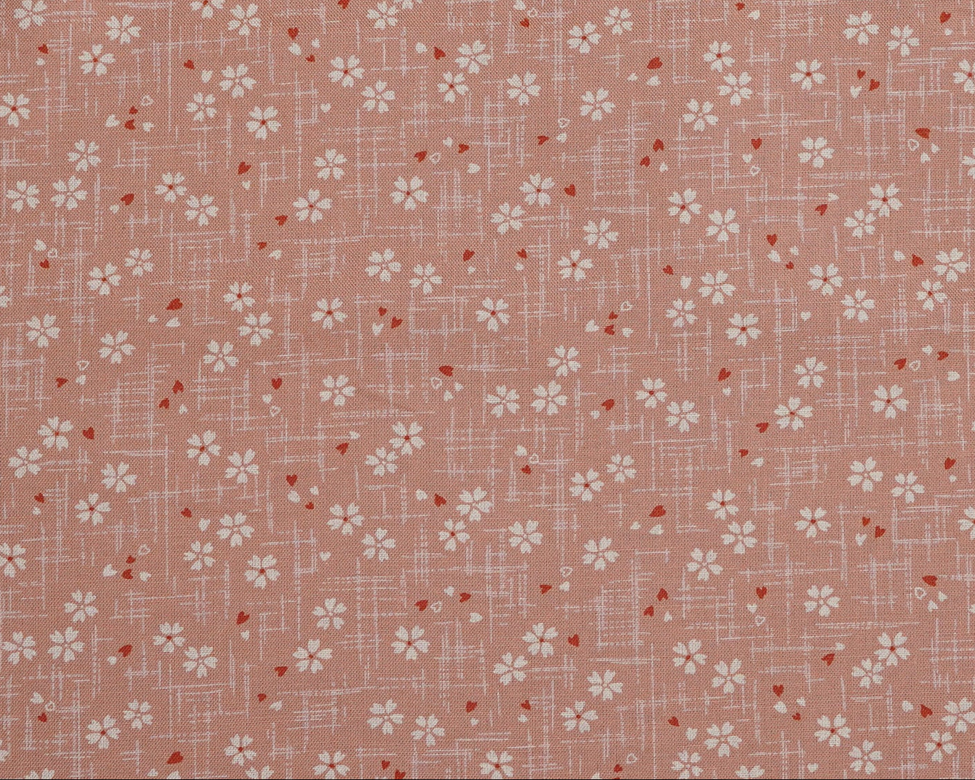 Floral patterned fabric with small white flowers on a pink background