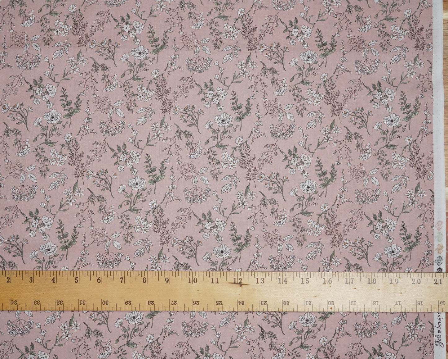 Floral patterned fabric with a ruler for scale on a pink background