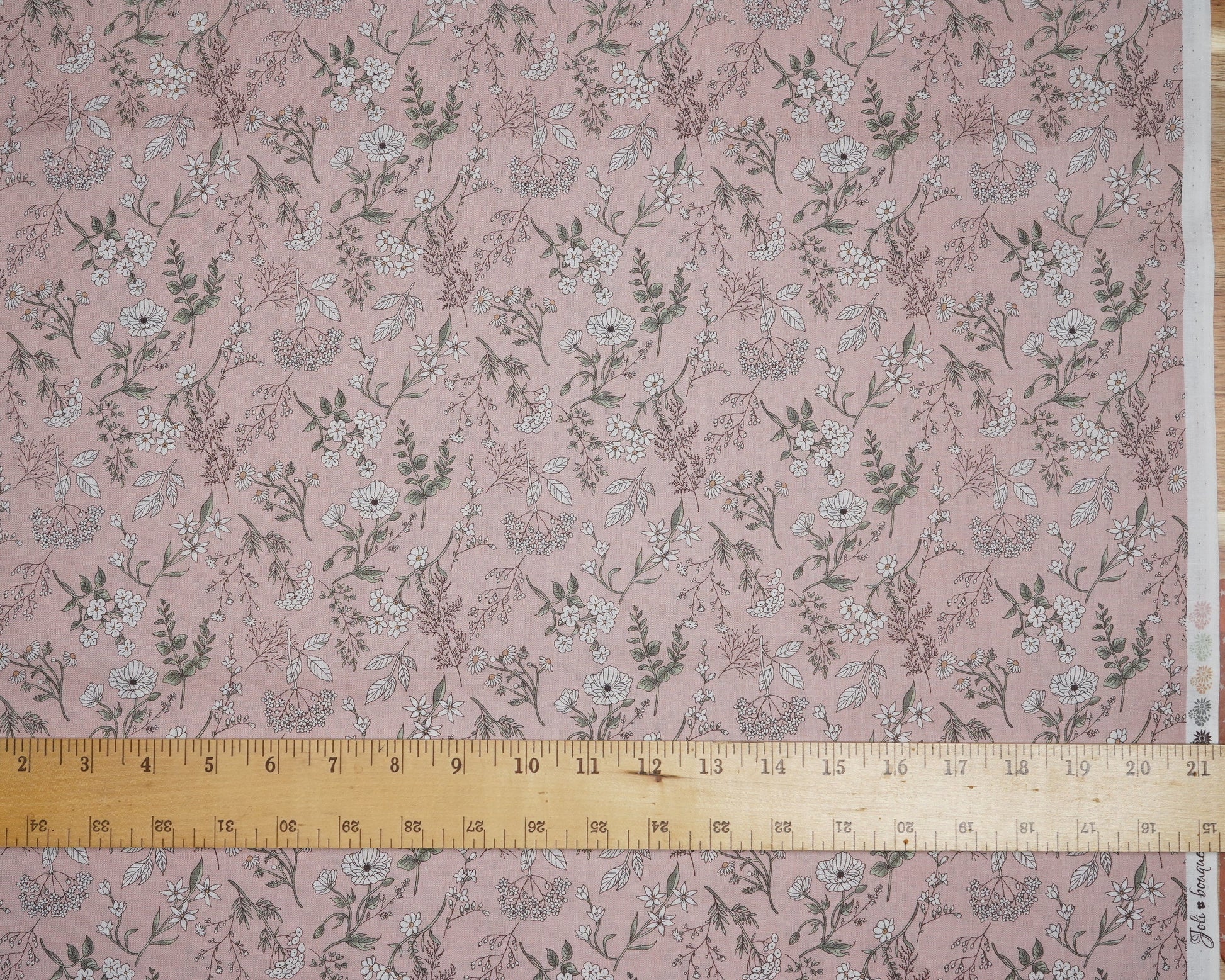Floral patterned fabric with a ruler for scale on a pink background