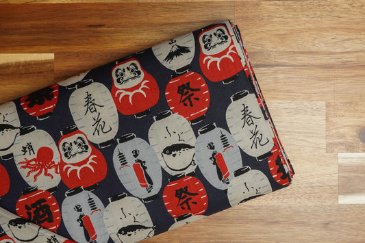 Darumas and Lanterns on Navy cotton fabric, folded on the bolt