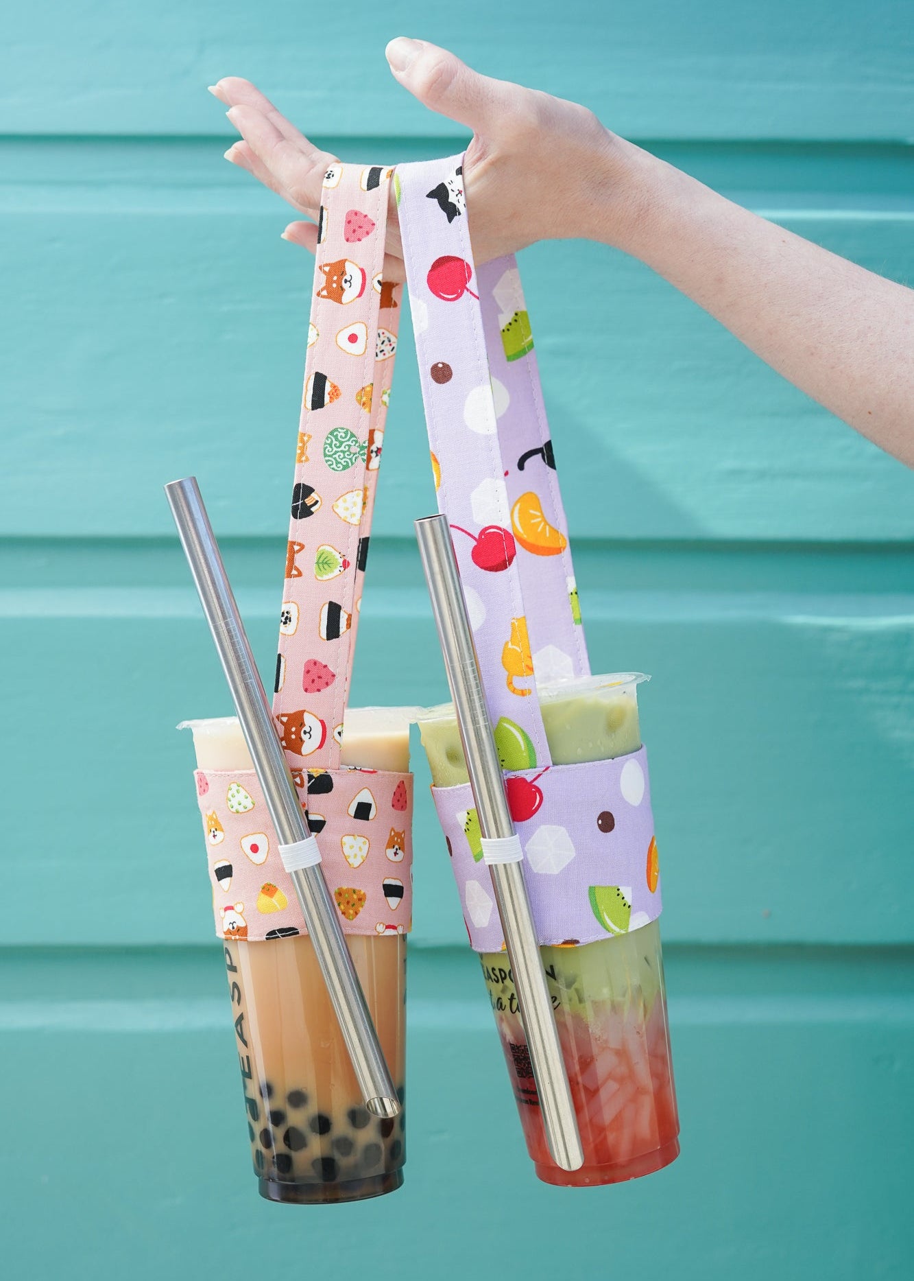 Two bubble tea cups with colorful straws against a teal background