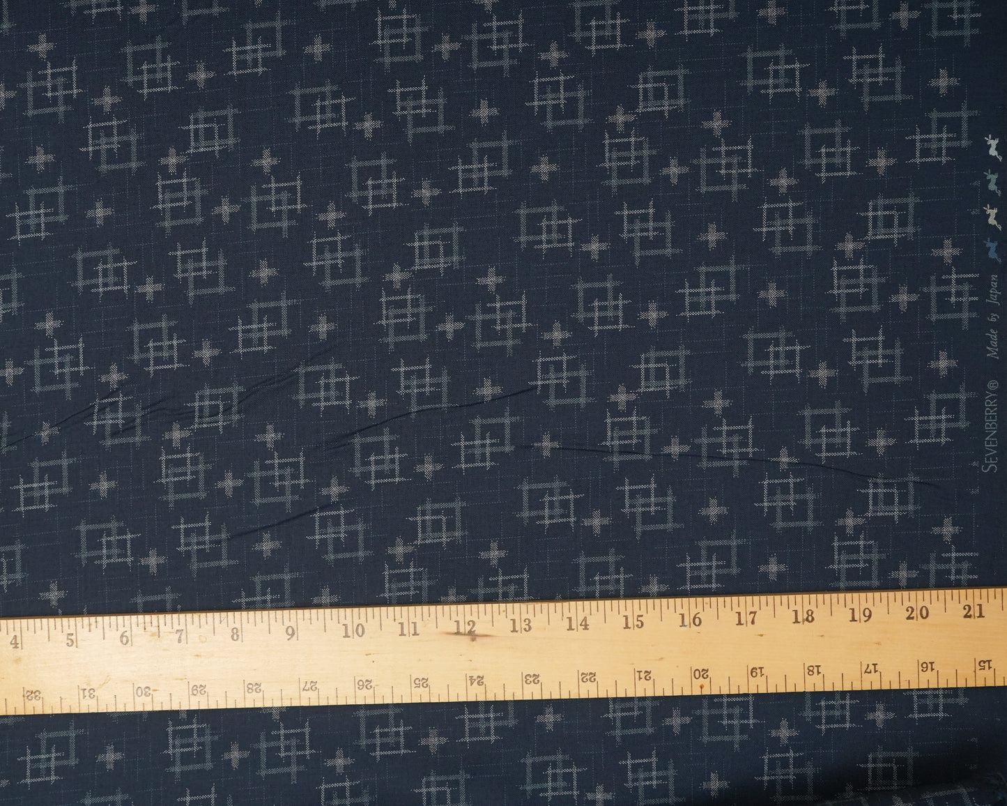 Navy fabric with a geometric pattern and a ruler at the bottom for scale.