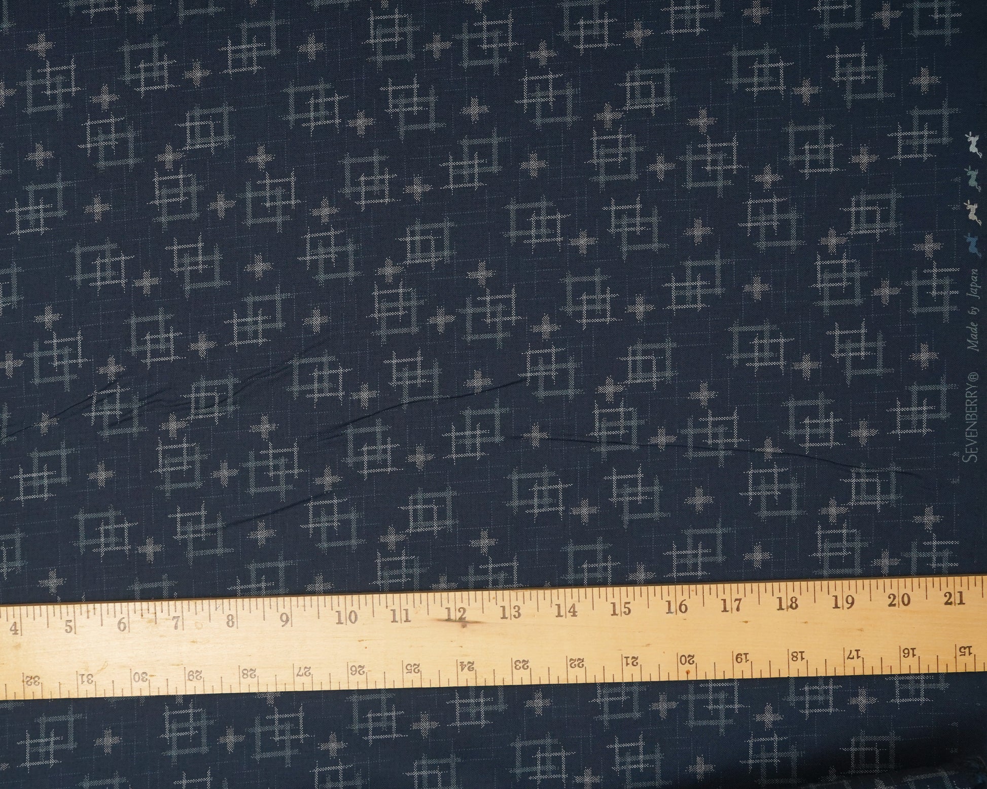 Navy fabric with a geometric pattern and a ruler at the bottom for scale.