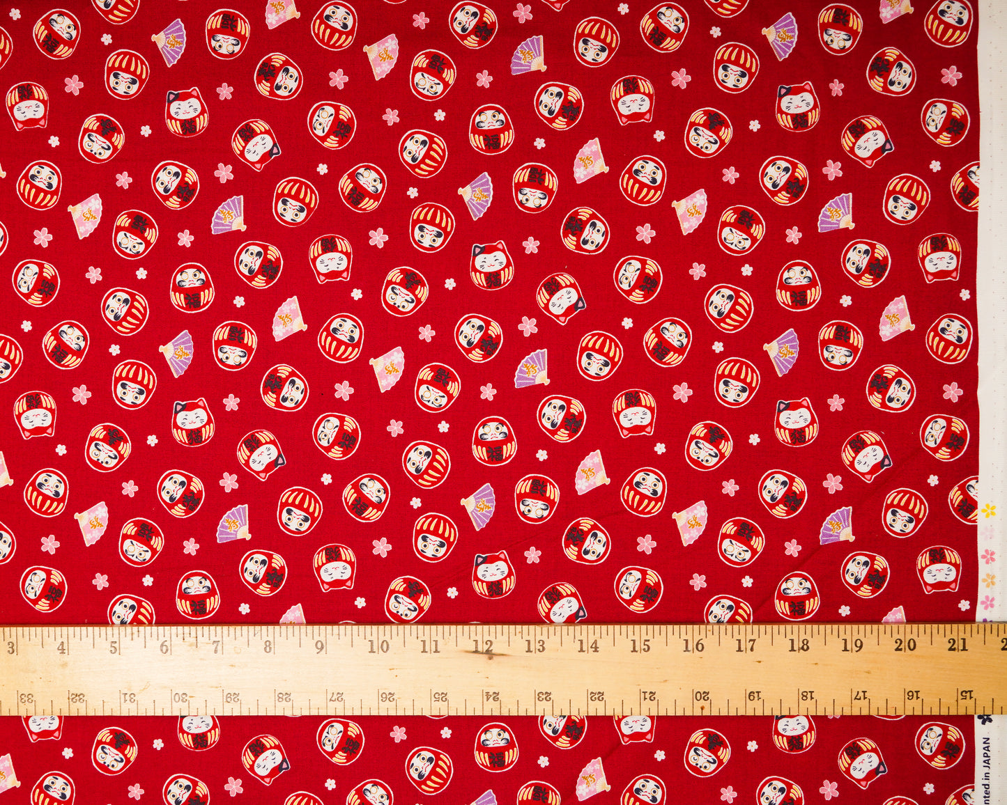 Red fabric with cartoon character pattern and ruler at the bottom