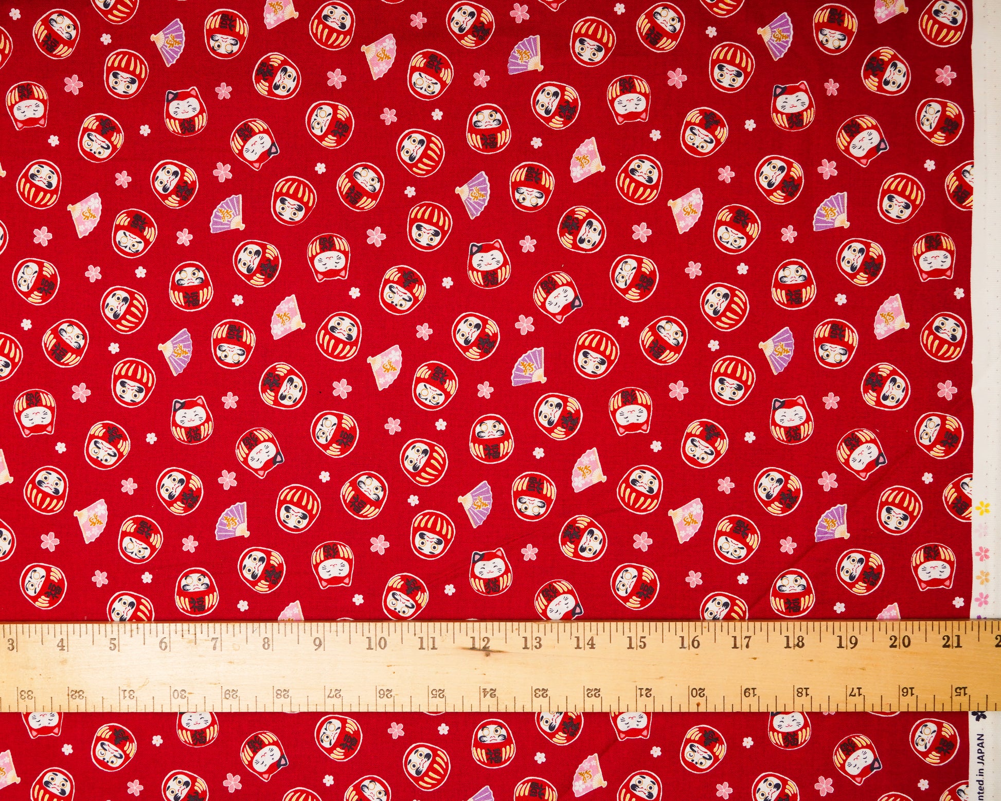 Red fabric with cartoon character pattern and ruler at the bottom