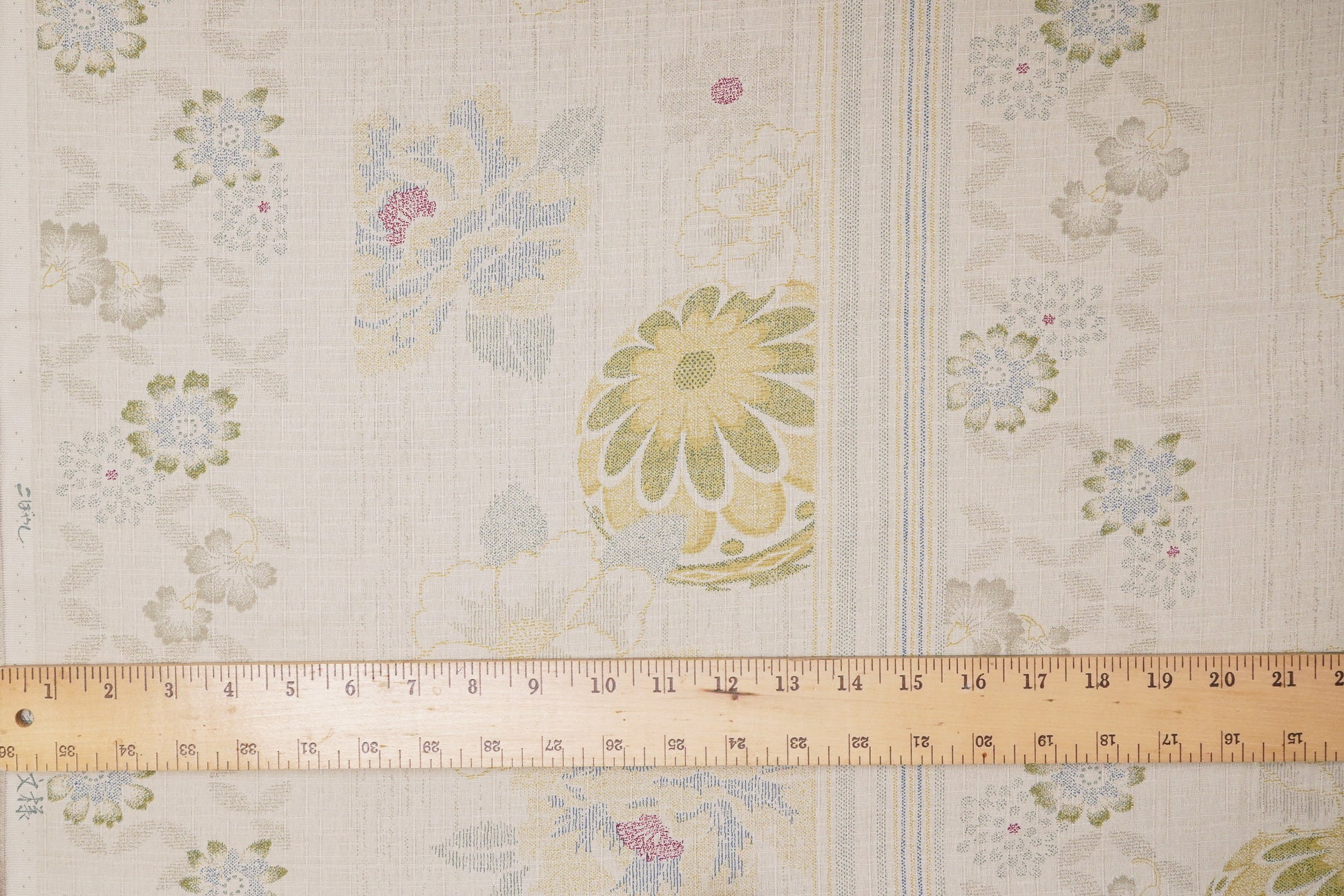 Floral patterned fabric with a ruler for scale on a beige background