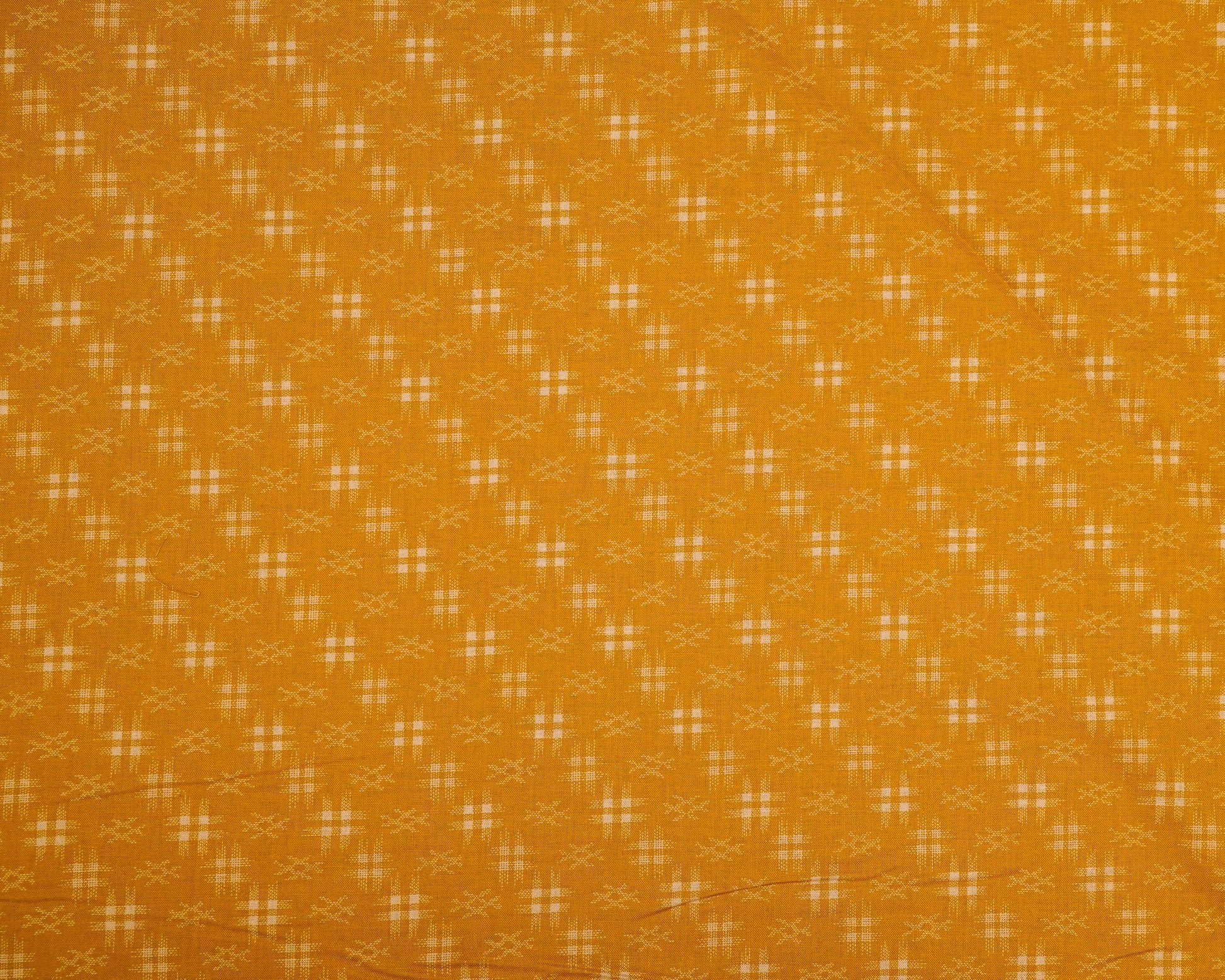 Patterned fabric with a small geometric design on a mustard yellow background