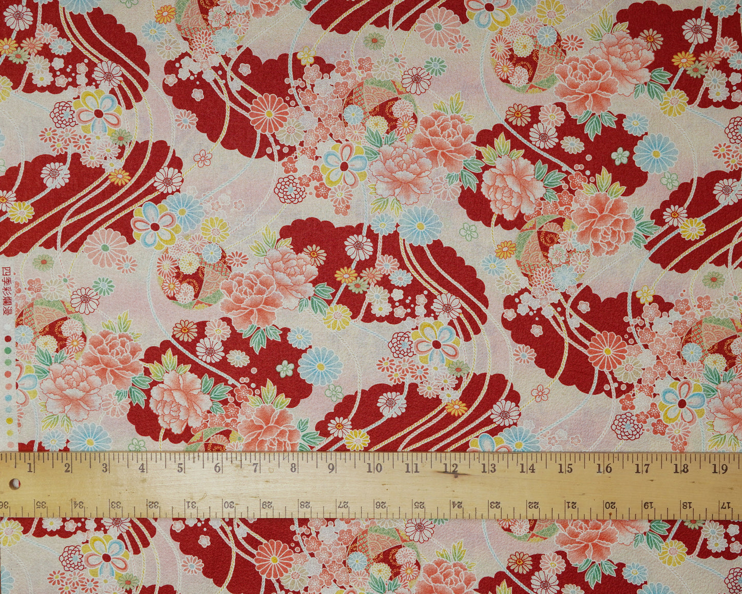 Floral fabric with red and pink patterns and a ruler at the bottom for scale.