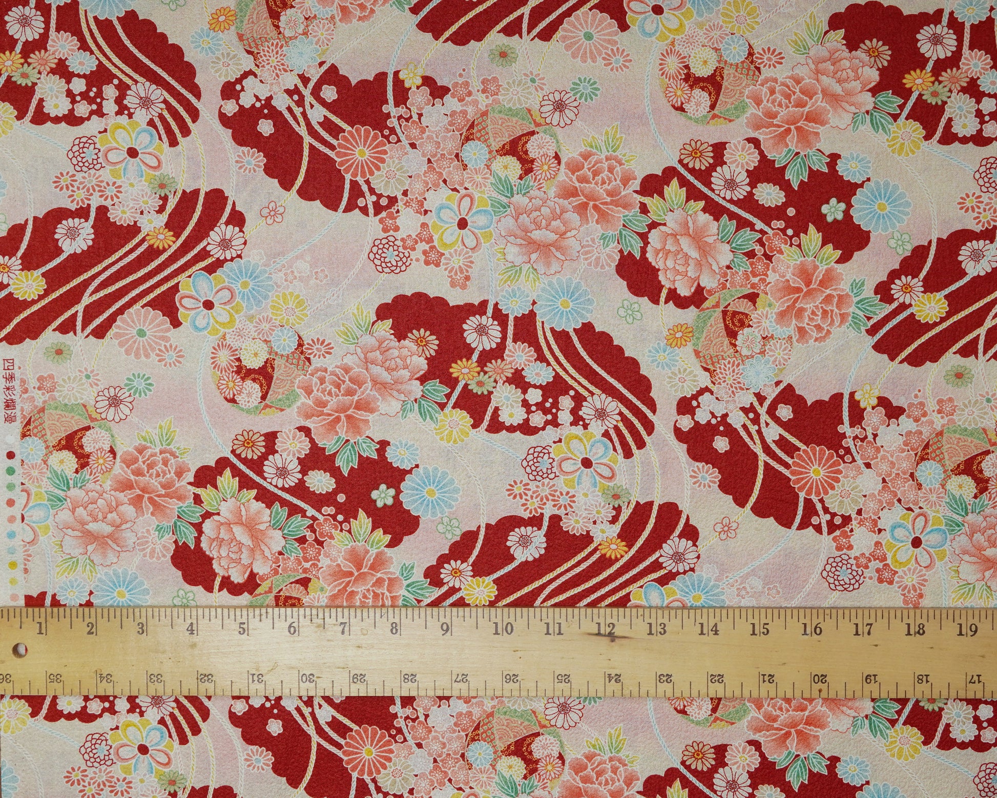 Floral fabric with red and pink patterns and a ruler at the bottom for scale.