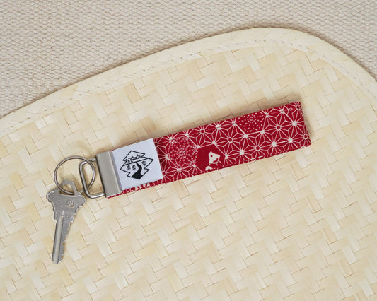 Red patterned keychain with a key on a textured beige surface