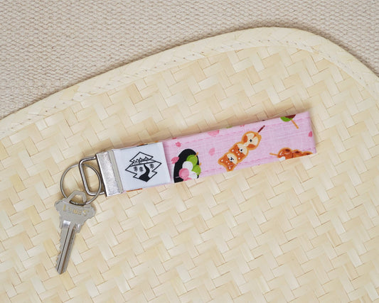 Keychain with shiba, sakura, and dango design on a textured surface