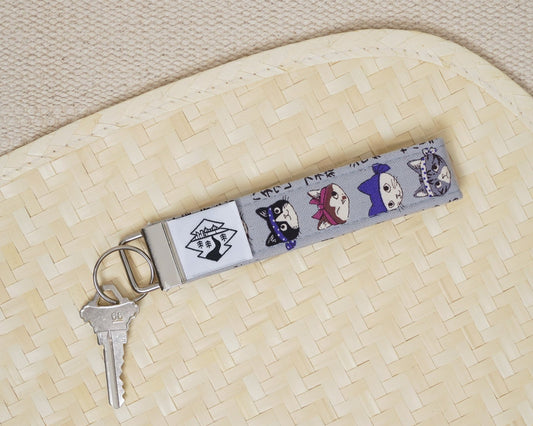 Keychain with cats wearing bandanas attached to a key on a textured surface