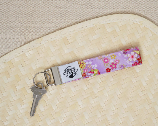 Floral keychain with a key on a textured beige surface
